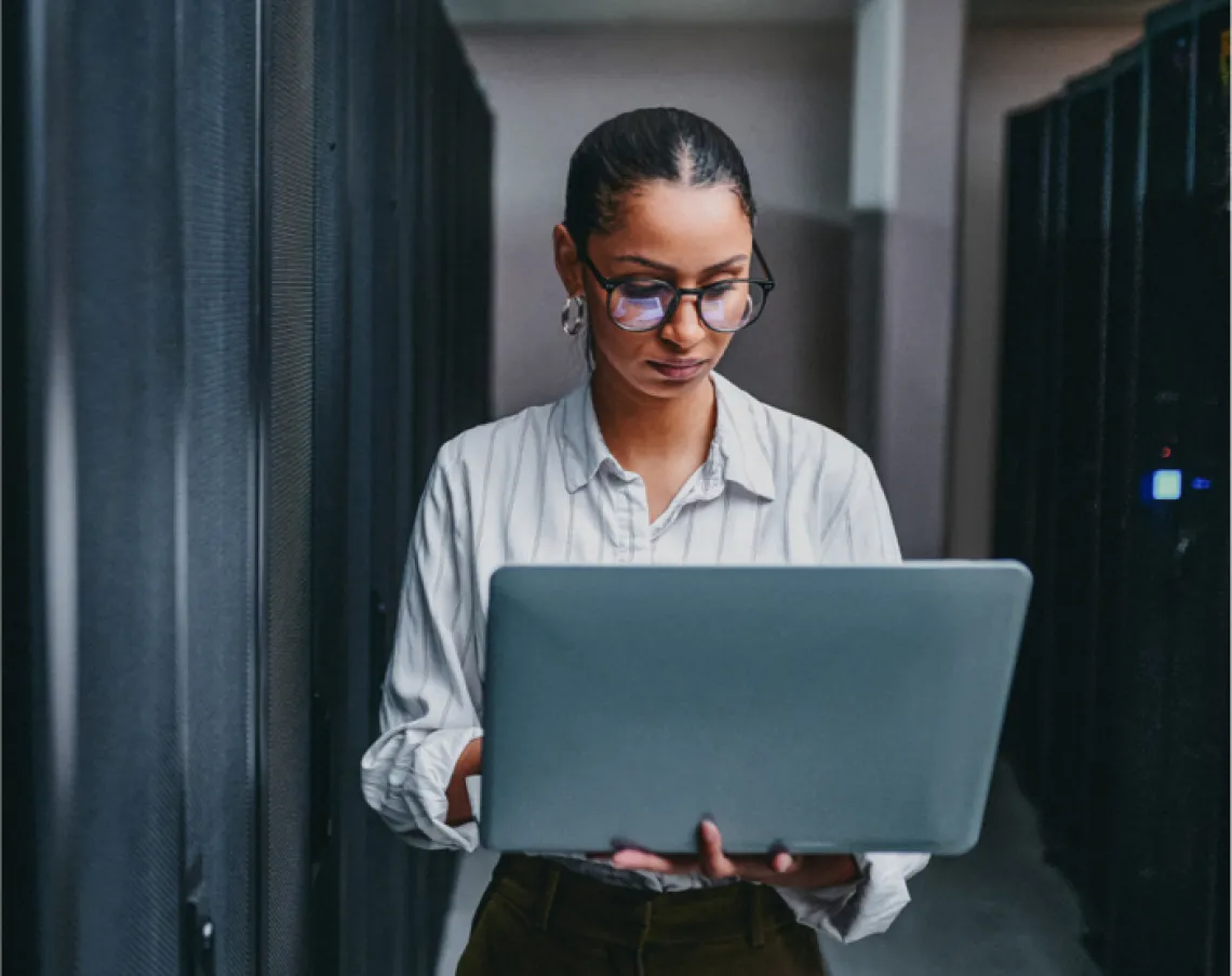 woman looking at laptop in server room